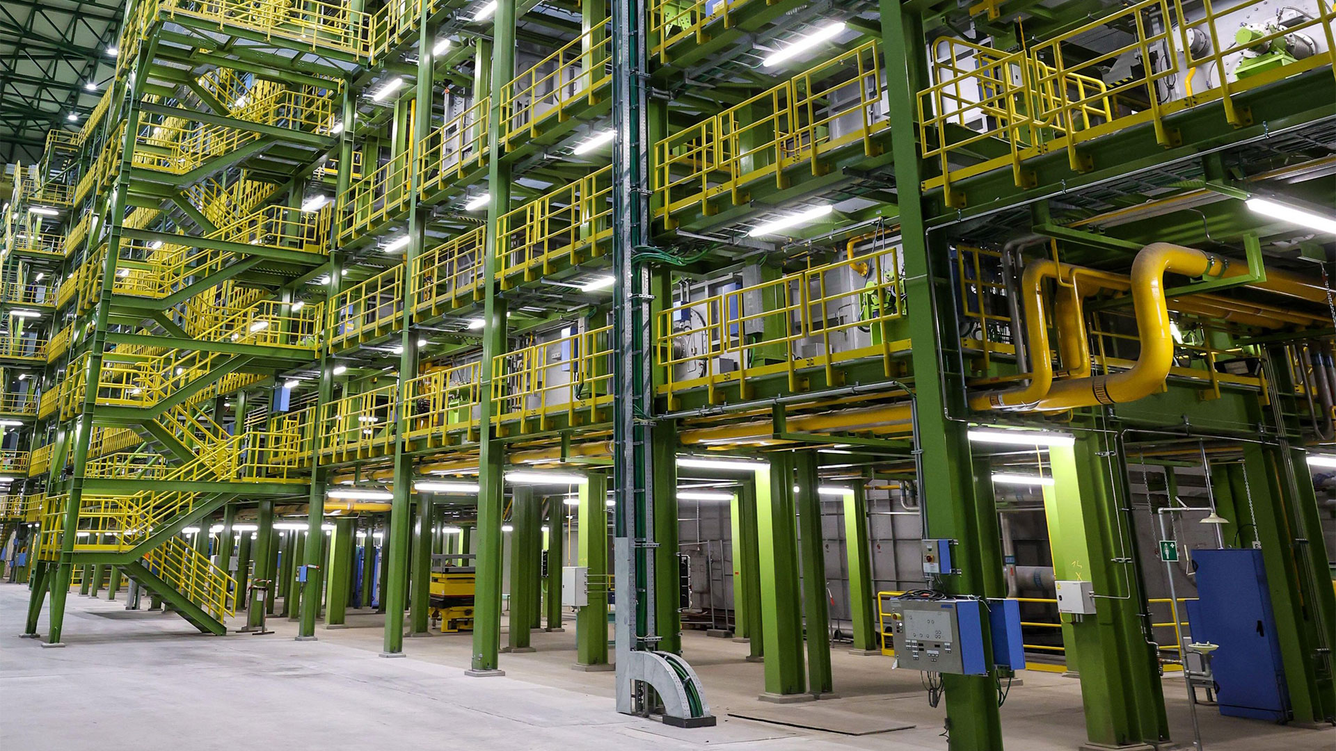 Industrieanlage mit grünen und gelben Regalsystemen, Treppen und Beleuchtung in einem modernen Lagerhaus.